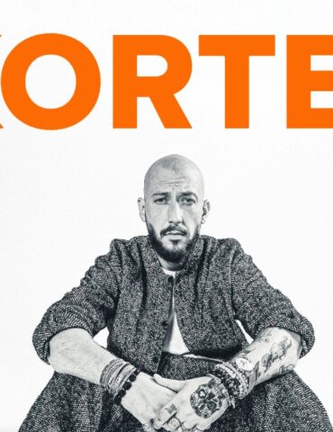 Poster for Kortesz tour: large orange 'KORTEZ' at top, a man seated in the center wearing a patterned suit and white sneakers; tour dates London and Manchester below.