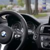 BMW car interior: steering wheel with logo, instrument cluster, and a navigation screen showing a map on the right side of the dashboard.