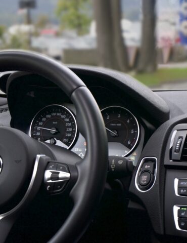 BMW car interior: steering wheel with logo, instrument cluster, and a navigation screen showing a map on the right side of the dashboard.