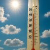 Outdoor thermometer with red mercury around 40°C against a bright, clear blue sky with sunshine.