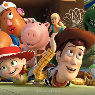 Woody, Buzz Lightyear, Jessie and a colorful group of Toy Story characters lie on the floor, smiling and peeking toward the camera.