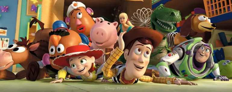 Woody, Buzz Lightyear, Jessie and a colorful group of Toy Story characters lie on the floor, smiling and peeking toward the camera.