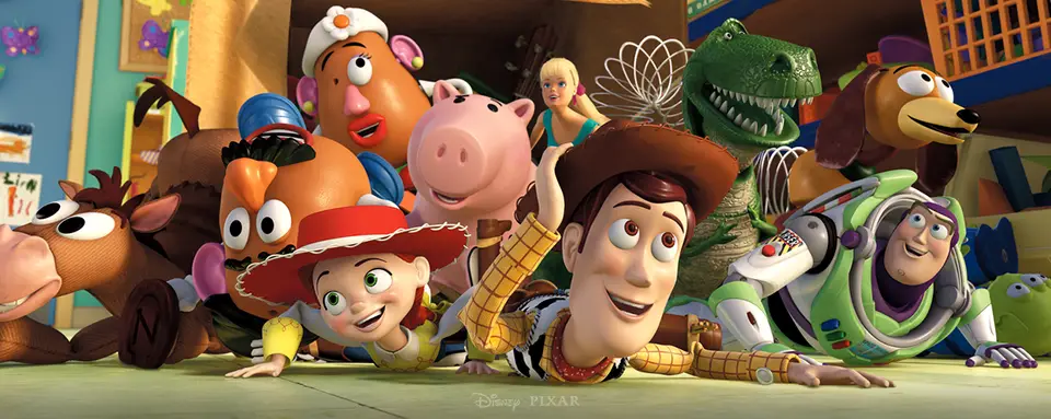 Woody, Buzz Lightyear, Jessie and a colorful group of Toy Story characters lie on the floor, smiling and peeking toward the camera.