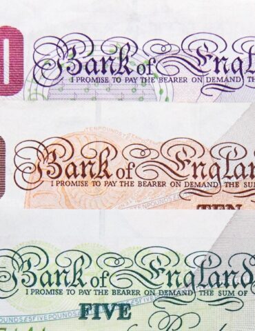 Close-up of UK Bank of England banknotes: £20, £10, and £5 with ornate script and 'Bank of England' text visible.