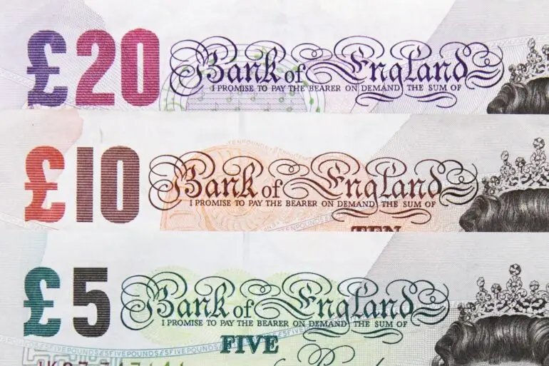 Close-up of UK Bank of England banknotes: £20, £10, and £5 with ornate script and 'Bank of England' text visible.