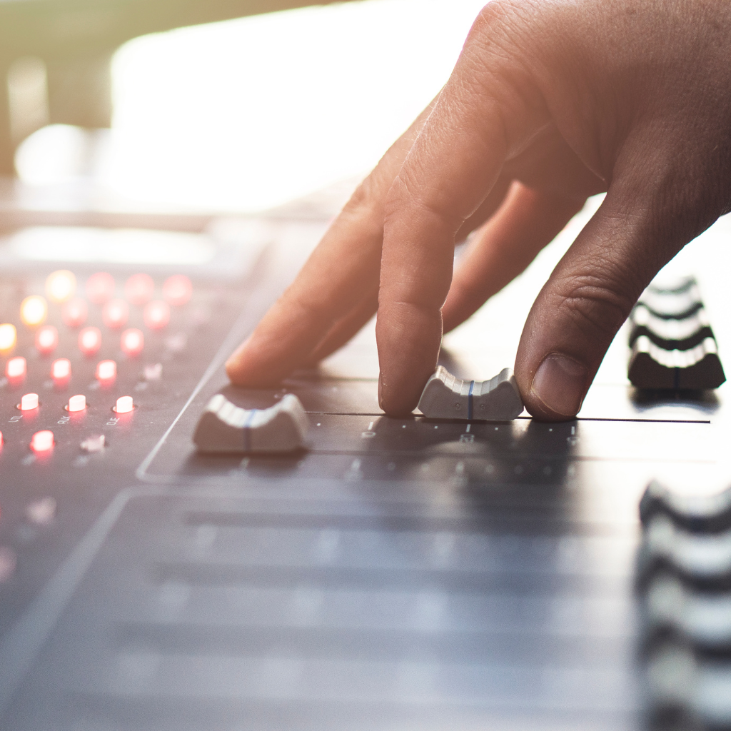 Close-up of a hand adjusting sliders on a professional audio mixer.