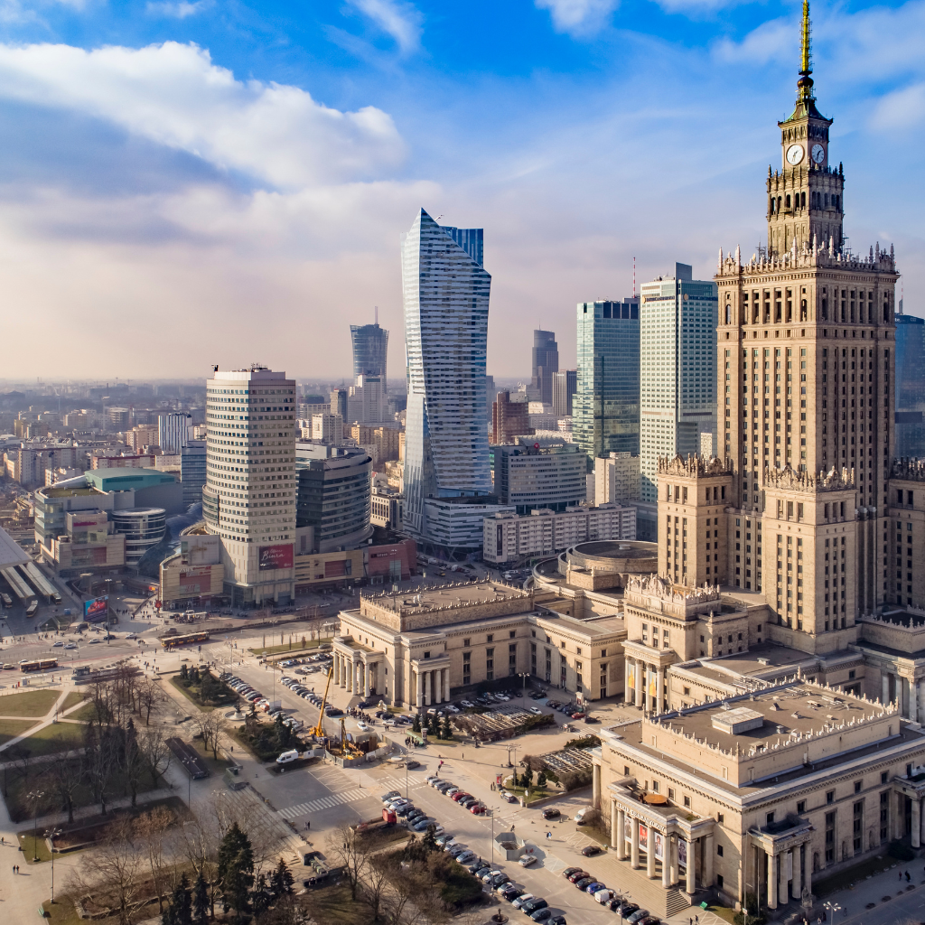 Aerial view of a European city skyline with a large historic tower building in the foreground and modern glass skyscrapers in the background.