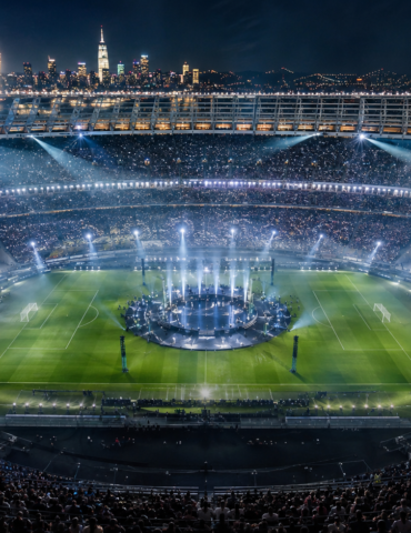 Nighttime stadium concert with a circular stage at the center, fireworks, and a packed crowd surrounding the field.