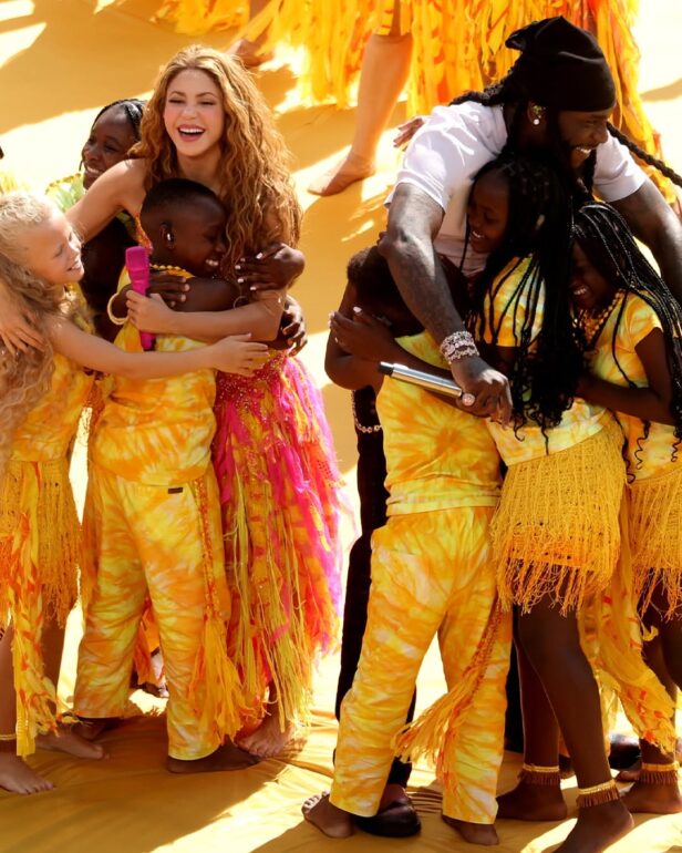 SHAKIRA - NOTE.radio - Polskie radio w UK | Polskie radio w Londynie Group of smiling people in yellow outfits hugging in a sunny outdoor event, celebrating together.