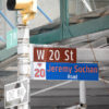 Intersection sign cluster: W 20 St and Jeremy Sochan Road with a One Way sign and construction scaffolding in the background.