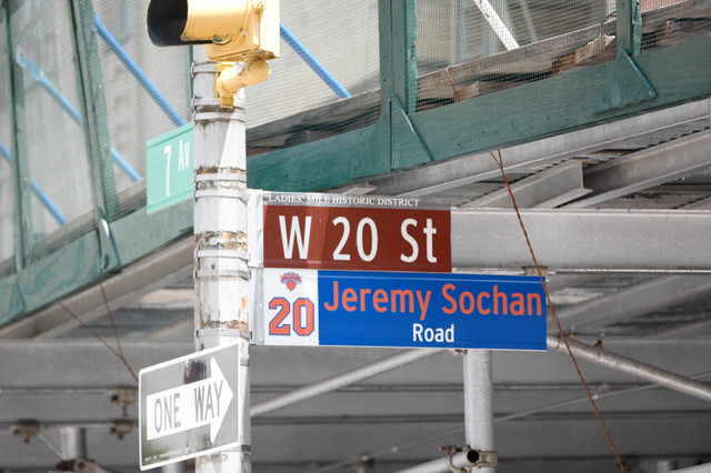 Intersection sign cluster: W 20 St and Jeremy Sochan Road with a One Way sign and construction scaffolding in the background.