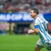 Soccer player in light blue and white striped jersey (number 10) runs on the field with a captain's armband during a match.