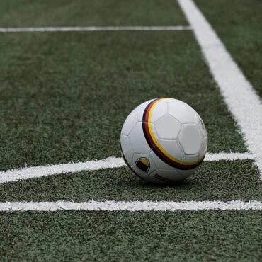 Soccer ball resting on a grassy field near white sideline markings. - Informative and concise option 1.