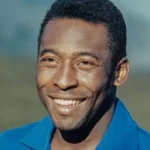 Pele - NOTE.radio - Polskie radio w UK | Polskie radio w Londynie Smiling man outdoors, head-and-shoulders portrait, wearing a blue shirt with a blurred natural background.