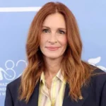 Julia Roberts - NOTE.radio - Polskie radio w UK | Polskie radio w Londynie Portrait of a woman with long red hair in a navy blazer at a blue film festival backdrop.