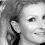 Black-and-white portrait of a smiling woman with light hair, facing slightly to the right.