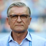 Adam Nawałka - NOTE.radio - Polskie radio w UK | Polskie radio w Londynie Older man with gray hair and glasses facing the camera, wearing a light blue shirt and a lanyard.