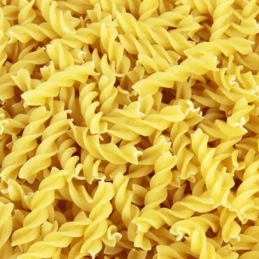 Close-up of uncooked fusilli pasta spirals piled together.