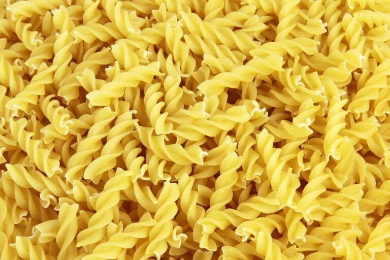 Close-up of uncooked fusilli pasta spirals piled together.
