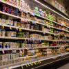 Aisle in a grocery store's refrigerated dairy section filled with yogurt cups and tubs on shelves.