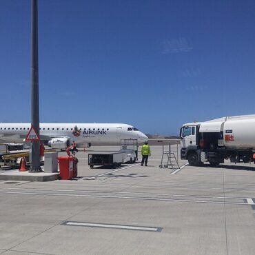 Airlink commuter jet on the tarmac with ground crew and a fuel truck nearby under a clear blue sky