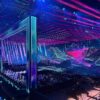 Futuristic nightclub stage with neon frames, purple-blue lasers, and a LED backdrop; crowd seated and watching a performance.