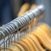 Close-up of metal spiral hangers on a clothes rack with wooden hangers blurred in the background.