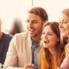 Ja-Lider! poster advertising Szkoła Lidera Polonijnego: recruitment ends 25 lipca; 7‑day trip to Poland (two dates); funded travel, lodging and meals; two training programs (onsite and online); meeting with a member of DWPPG MSZ. Photo of a diverse group smiling at a round table.