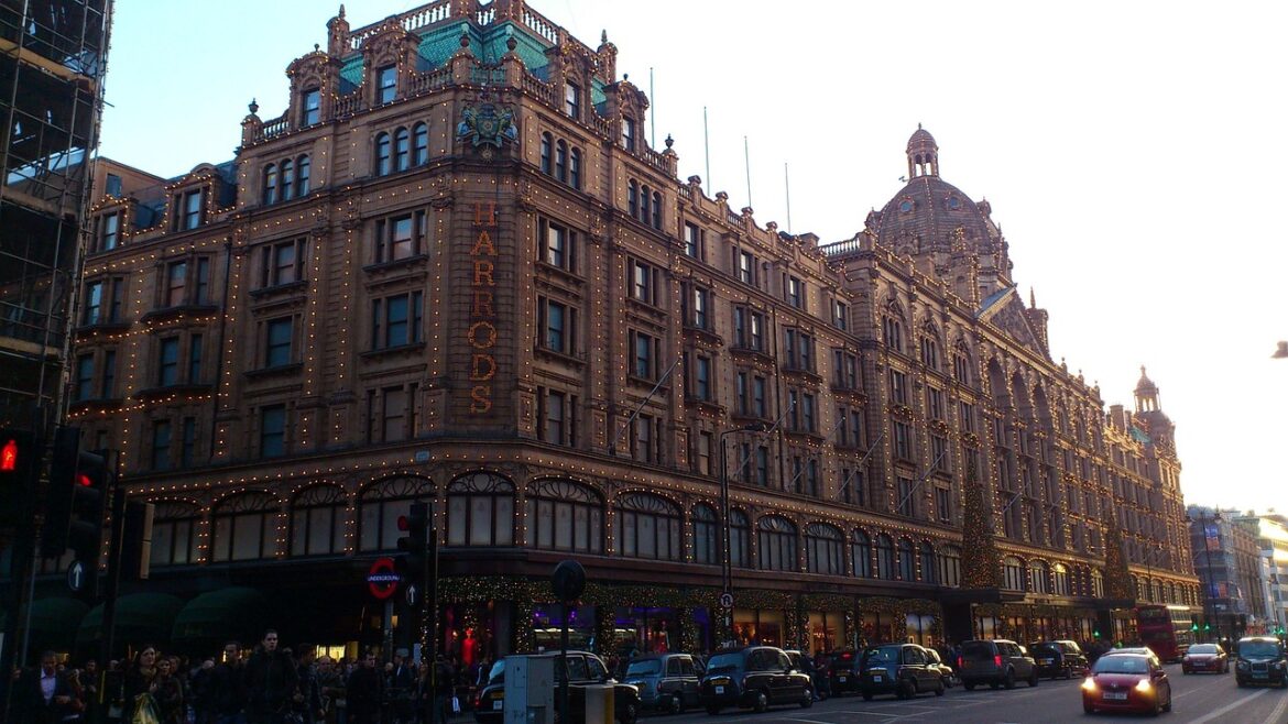 Harrods department store façade lit with festive string lights on a busy London street at dusk.