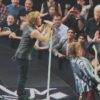 Rock singers perform on stage with fans in the front row reaching out and taking photos beyond them