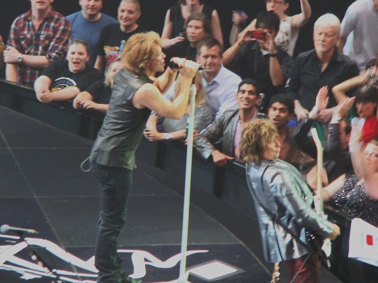 Bon_Jovi_O2_Arena_Circle_Tour - NOTE.radio - Polskie radio w UK | Polskie radio w Londynie Rock singers perform on stage with fans in the front row reaching out and taking photos beyond them