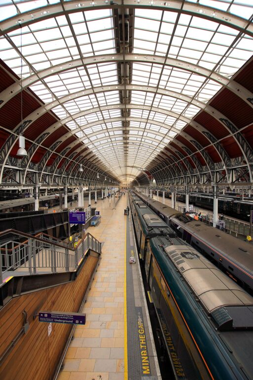 Inside a large train station with a curved glass and steel roof and trains at the platforms beneath it
