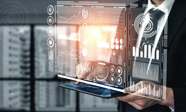 Business professional holding a tablet with holographic data dashboards and charts projected in front of him/her.