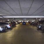 Underground parking garage with cars parked on both sides and a central driving lane.