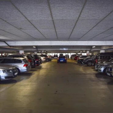 Underground parking garage with cars parked on both sides and a central driving lane.