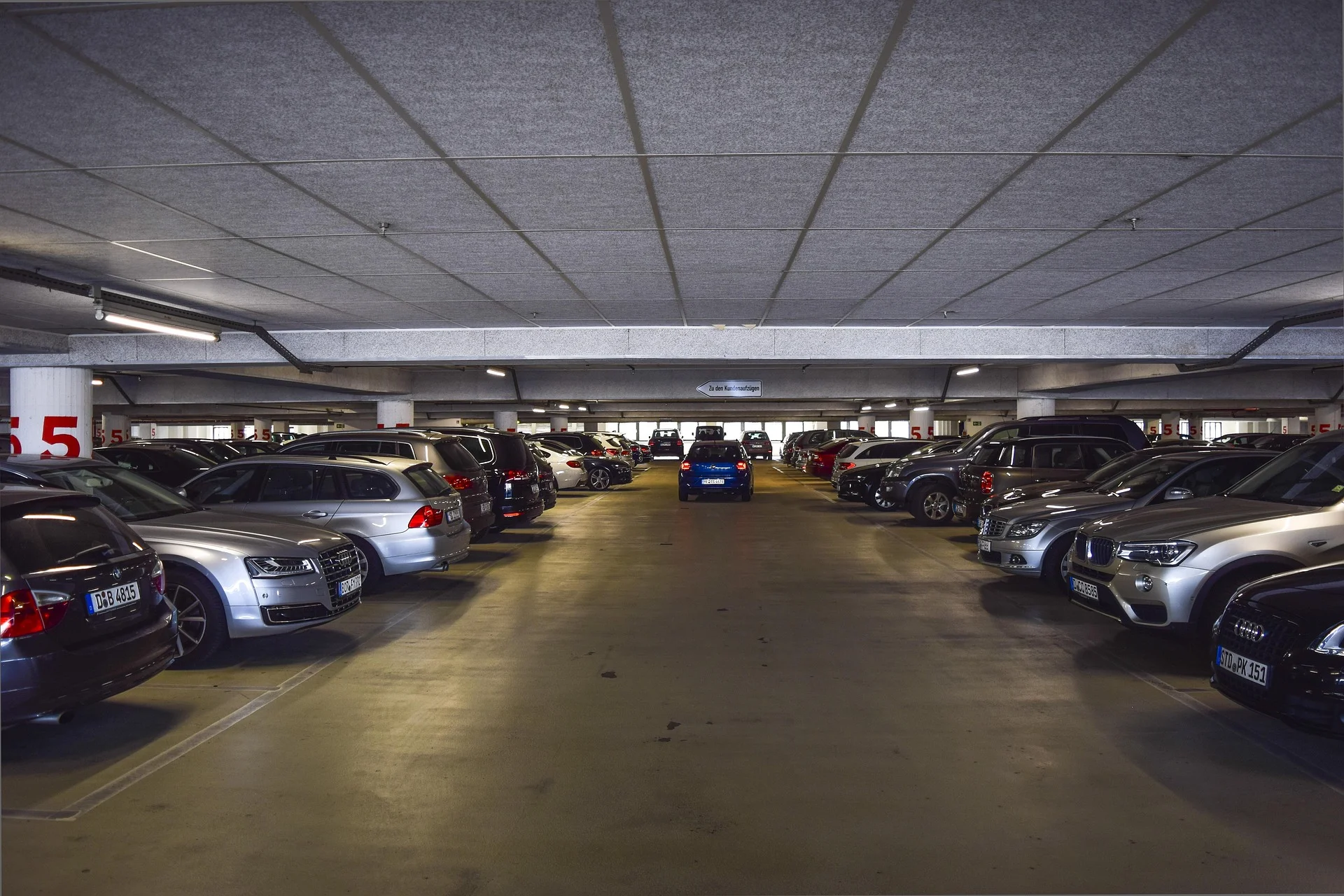 Underground parking garage with cars parked on both sides and a central driving lane.