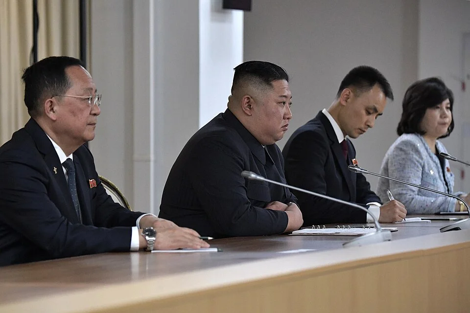 Four panelists seated at a long conference table with microphones, participating in a formal meeting.