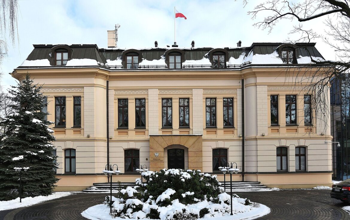 Constitutional Tribunal building in winter, with snow on the ground and a Polish flag atop the roof.