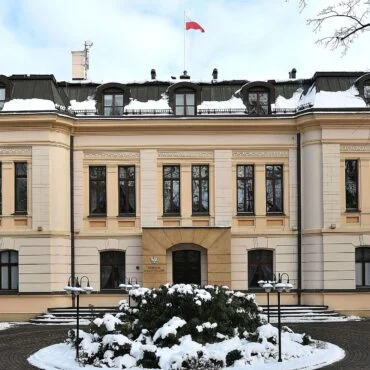 Constitutional Tribunal building in winter, with snow on the ground and a Polish flag atop the roof.