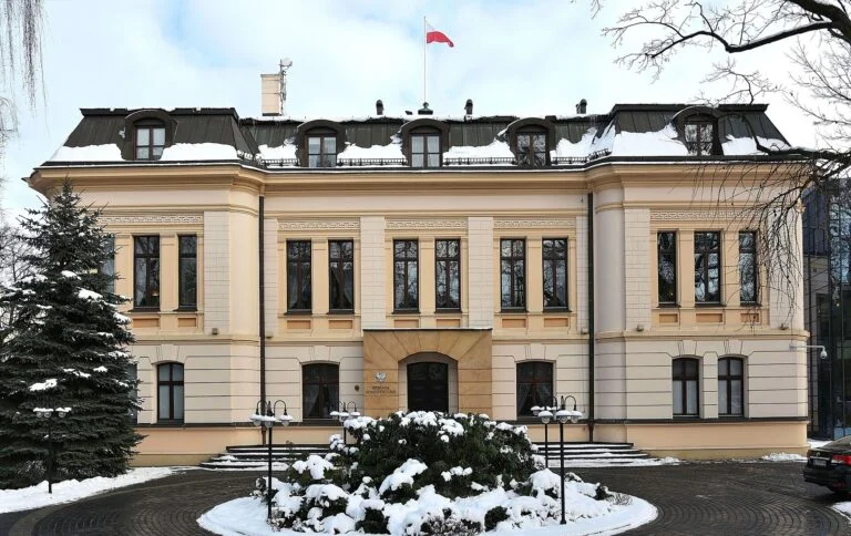 Constitutional Tribunal building in winter, with snow on the ground and a Polish flag atop the roof.