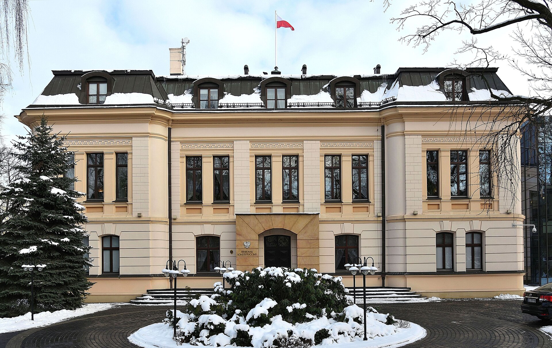 Constitutional Tribunal building in winter, with snow on the ground and a Polish flag atop the roof.