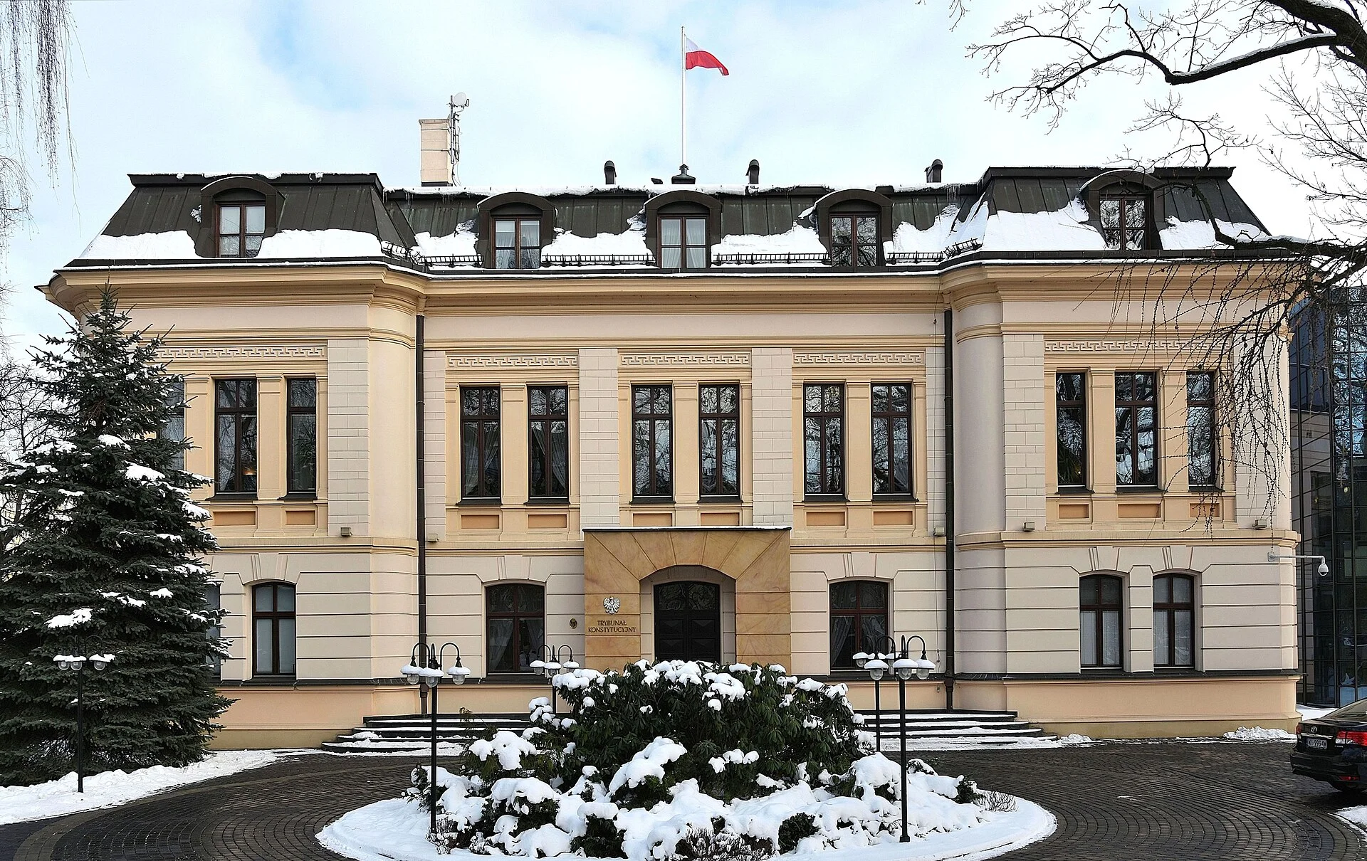 Constitutional Tribunal building in winter, with snow on the ground and a Polish flag atop the roof.