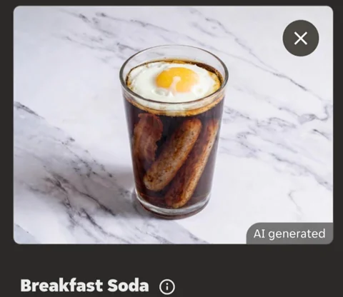 Glass of dark breakfast soda with a sunny-side-up egg on top and two sausages inside, on a marble surface.