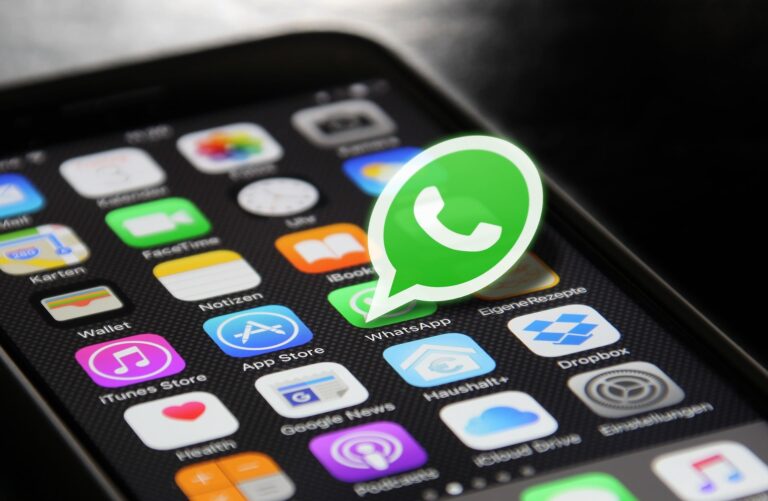 Logo WhatsApp na ekranie telefonu z informacją o nowych opłatach za wybrane wiadomości biznesowe.