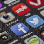 Close-up of a smartphone home screen showing social apps like Instagram, Facebook, and Twitter with colorful icons.