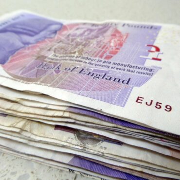 Stack of £20 Bank of England notes fanned on a light surface.