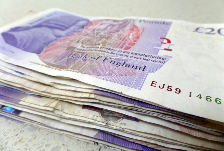 Stack of £20 Bank of England notes fanned on a light surface.