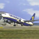 Ryanair Boeing 737 lifting off the runway at an airport, wheels still extended with terminal building in the background