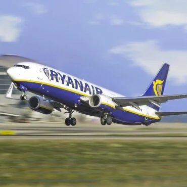 Ryanair Boeing 737 lifting off the runway at an airport, wheels still extended with terminal building in the background