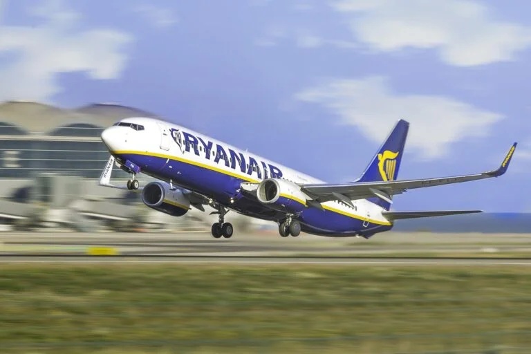 Ryanair Boeing 737 lifting off the runway at an airport, wheels still extended with terminal building in the background